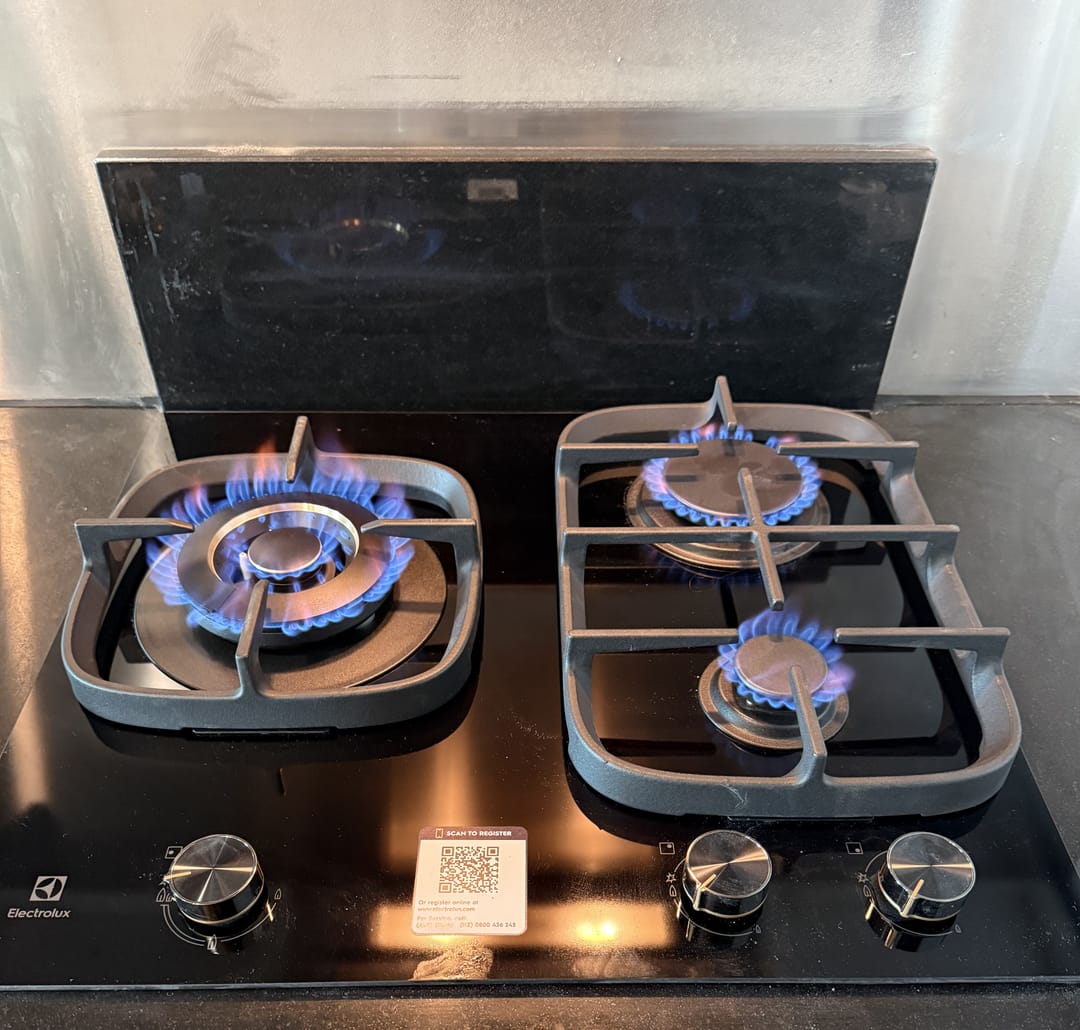 Licensed gasfitter flame testing a newly installed gas cooktop